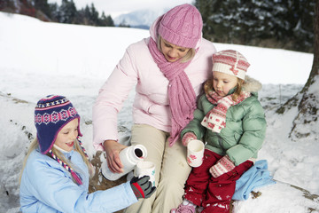 Mother pouring hot tea in daughter's cups