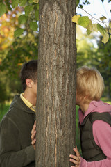 Teenage couple kissing behind a tree, selective focus