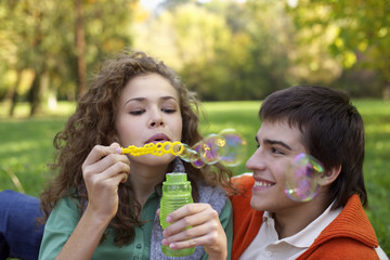Teenage boy and girl making soap bubbles, close-up, selective focus