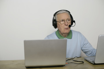 Senior man with headset using a laptop, fully_released