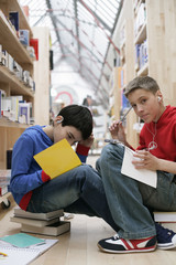 Two boys reading in a library and listening to music by MP3-Player, fully_released