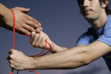 Young man is tying an other man's hands up , close-up