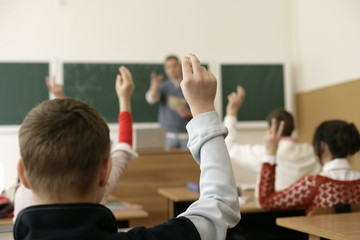 View inside a classroom, pupils raising arms