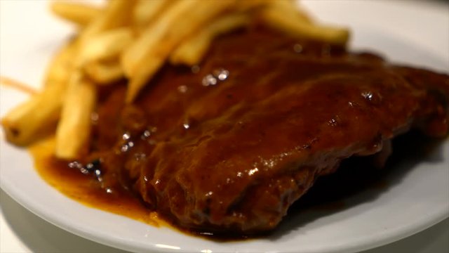 Half rack of BBQ pork ribs with french fries on plate, selective focus
