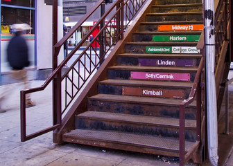 Man walking past a metal stairway to elevated train platform in Chicago's south loop at Adams and Wabash.