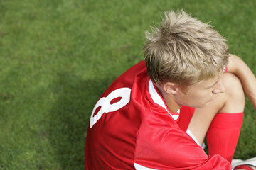 Naklejka premium Soccer player sitting on grass