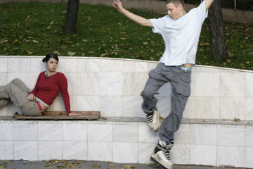 Boy inline skating over a border while a young girl watching him