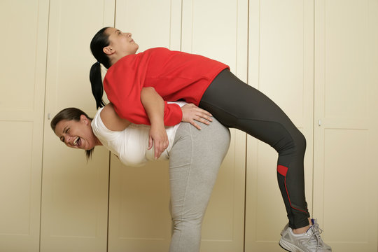 Full figured woman pulling another woman over her back