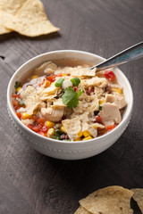 Chicken Tortilla Soup on wooden background with chips with spoon