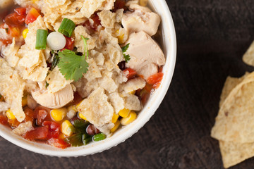 Chicken Tortilla Soup on wooden background with chips close up above shot