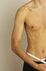 Fototapeta premium Mężczyzna mierzący swoją talię - próżność - fizyczność - dokładność