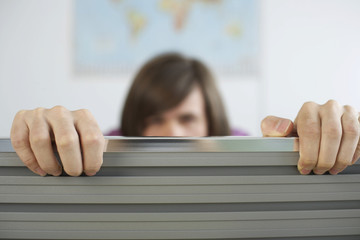 Young man hiding behind a partition