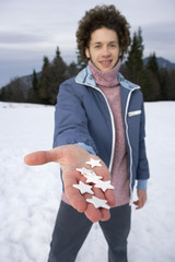 Young man with stars in his hand in a winterly landscape, selective focus