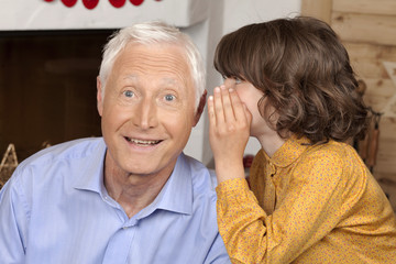 Girl whispering to grandfather
