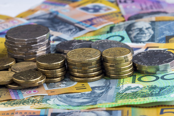 Australian money notes spread out and coins stacked up.