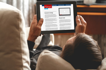 Senior reading news on tablet. Looking information