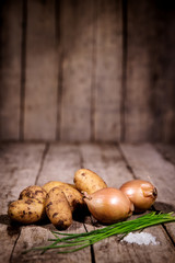 Kartoffeln, Zwiebeln, Schnittlauch und Salz auf Holz mit Textfreiraum