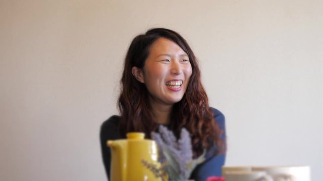 Japanese woman laughing at a cafe.