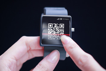 Hand scanning QR code on smartwatch.