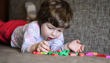 Naklejka premium child playing with small toys on the couch in room
