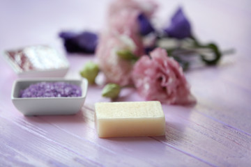 Spa concept. Soap with scrubs and flowers on white wooden background