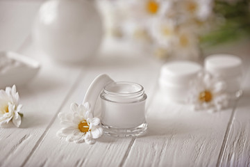 Obraz na płótnie Canvas Spa concept. Nourishing cream and daisy flowers on white wooden table