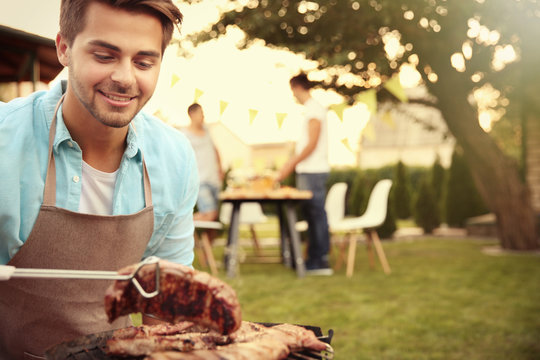 Handsome Young Man Preparing Barbecue Steaks On Grill