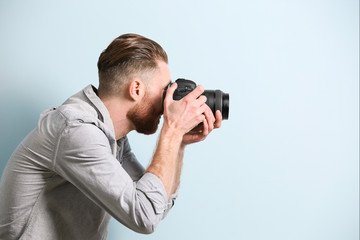 Fototapeta premium Handsome photographer on color background