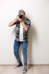 Handsome young photographer on light wall background