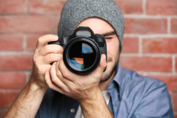 Handsome young photographer with camera on blurred background, closeup