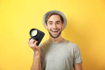Handsome young photographer on color background