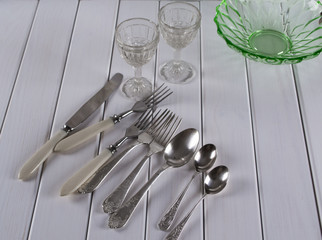Antique cutlery, glasses and vintage glass plate  on light background