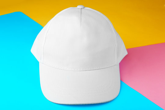 Blank white baseball cap on color paper background