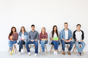 Group of people reading books while sitting near light wall