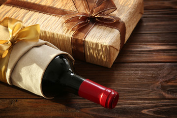 Decorated wine bottle and gift box on wooden background © Africa Studio