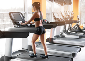 Fototapeta na wymiar Sporty woman running on treadmill at gym