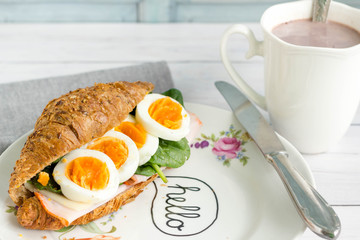 Breakfast whole wheat croissant sandwich with hot chocolate.