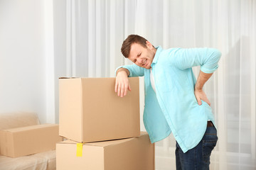 Young man suffering from pain after moving heavy box