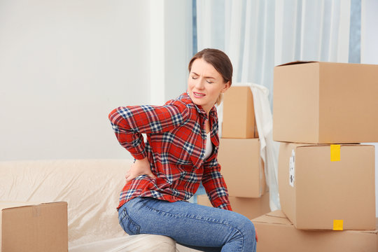 Young woman suffering from pain after moving heavy box