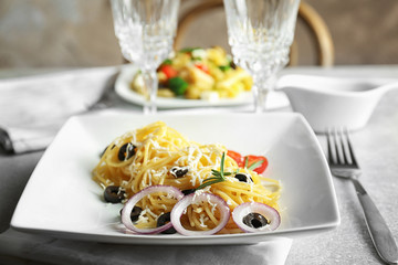 Plate of pasta salad with olives and cheese on table