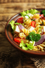 Cold delicious pasta salad on wooden table