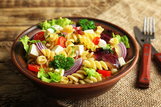 Cold delicious pasta salad on wooden table