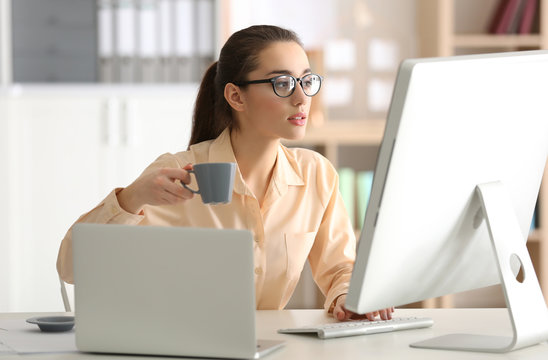 Young woman working and drinking coffee at office