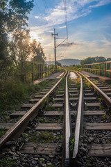 Fototapeta na wymiar railway tracks just before sunset, against the sun view (vertical frame)