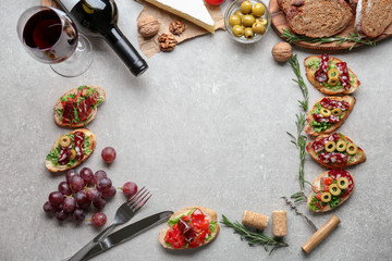 Wine with tasty bruschetta and ingredients on grey background