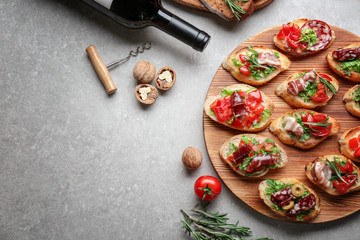 Wine with tasty bruschetta and ingredients on grey background