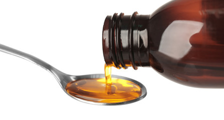 Pouring cough medicine syrup into spoon on white background