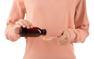 Woman pouring cough medicine syrup into spoon on white background