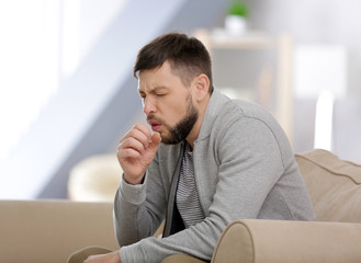 Young ill man sitting on sofa at home