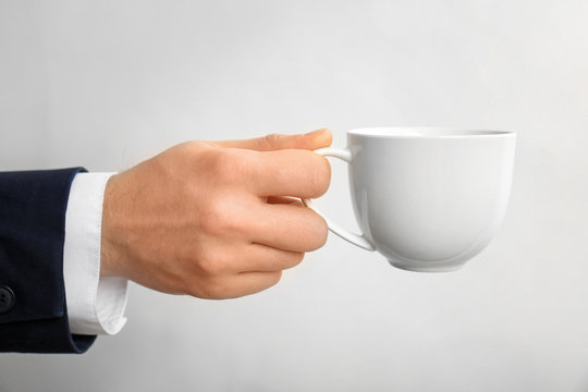 Male hand holding cup on white background